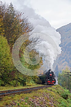 Vintage black steam locomotive train with wagons on railway.