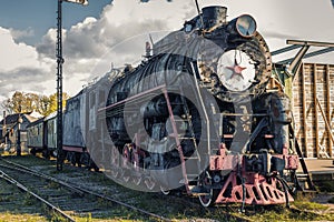 Vintage black steam locomotive train with wagons on station.