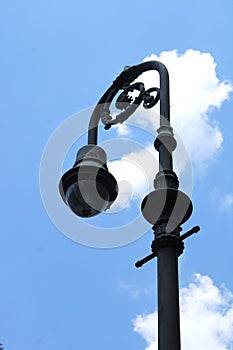 Vintage black street light in historic Savanah Georgia. Clear blue sky with bright white puffy cloud.