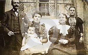 Vintage black and white photo of a Victorian family in front of house 1880s - 1900s.