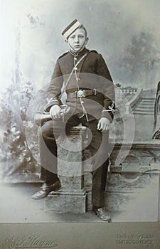 Vintage black and white photo of a young boy in military uniform holding a bugle.