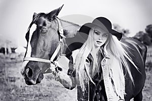 Vintage black and white portrait of a young beautiful caucasian girl holding a horse
