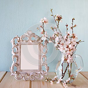 Vintage blank frame next to white spring flowers. selective focus. template, ready to put photography