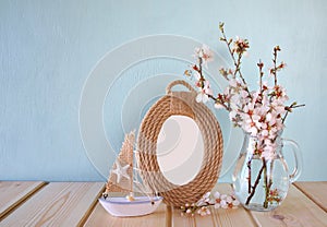 Vintage blank frame, sailboat next to white spring flowers. selective focus. template, ready to put photography