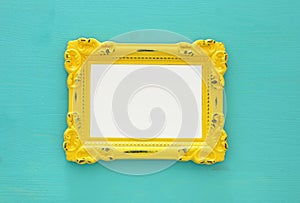 Vintage blank yellow photo frame over mint background. Ready for photography montage. Top view from above.