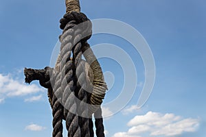 Vintage block and tackle with elaborate knots and wrapping on an old sailing vessel against a blue sky with clouds