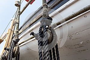 Vintage block and tackle with wrapped ropes against the hull of an old wooden lifeboat, nautical theme
