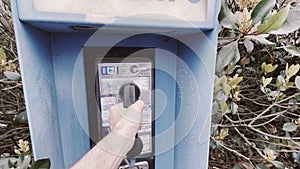 Vintage Blue outdoors public payphone booth hand picking up