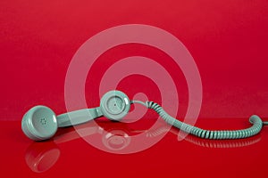 Vintage blue telephone receiver lying on a red background