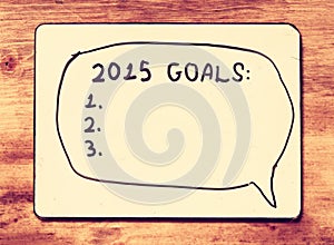 Vintage board with phrase 2015 goals over wooden table. retro vintage filter