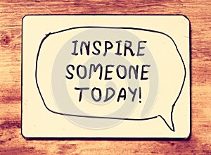 Vintage board with the phrase inspire someone today! written on it. retro filtered image