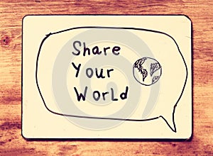 Vintage board with the phrase share your world written on it. retro filtered image