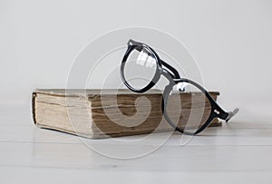 Vintage book with black reading glasses on top