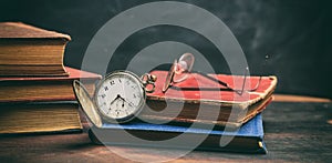 Vintage books and pocket watch on dark background