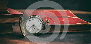 Vintage books and pocket watch on dark background