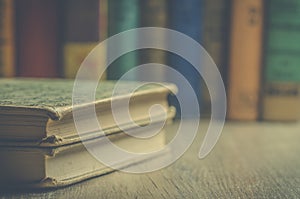 Vintage books on a wooden bookshelf with books in background