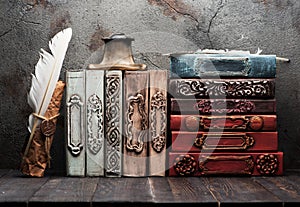 Vintage books on a wooden shelf, paper scroll with a wax seal, iinkwell and feather for writing