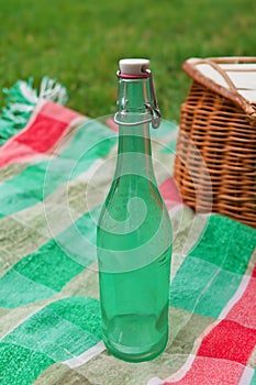 Vintage bottle with liquid on a picnic red and green blanket