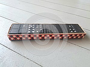 Vintage Box with Black and White Plastic Dominoes on Grey Wooden Floor