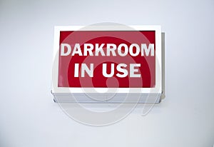 Vintage box shaped sign stating Darkroom In Use with white letters on a red background