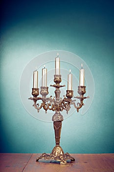 Vintage brass candelabrum with five burning candles in front mint blue background