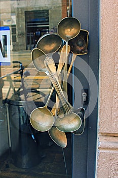 Vintage brass door handle designed from aged big spoons  scoops on glass door with blurred reflection in front of bistro cafe.