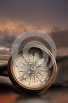 Vintage brass navigation compass with dark clouds