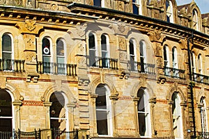 Vintage brick building facade with ornate windows and architectural details under a clear blue sky in Harrogate, England
