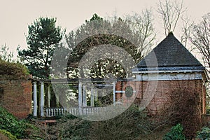 Vintage brick gazebo with classic columns in a serene garden setting during dusk