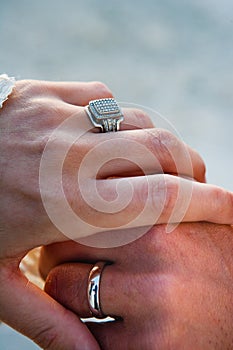 A vintage bride and groom rings on embracing hands after being married at a wedding