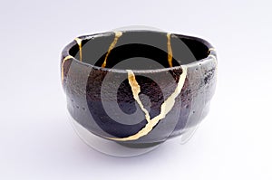 Vintage broken black tea ceremony bowl repaired with gold kintsugi technique photo