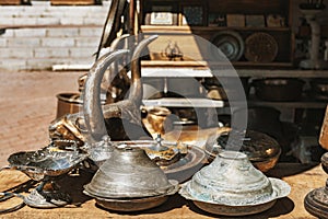 Vintage bronze animal statue, mortars, silver and copper plates, frames and other ornaments on counter top in a shop at bazaar