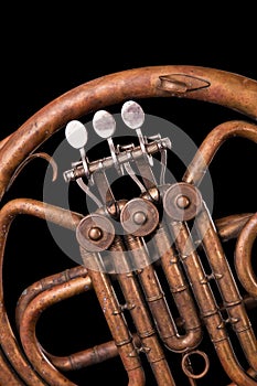 Vintage bronze pipes, valve, key mechanical elements french horn, black background. Good pattern, prompt music instrument.