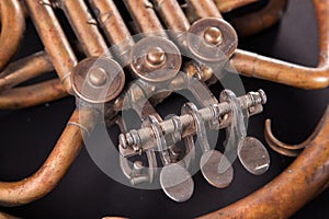 Vintage bronze pipes, valve, key mechanical elements french horn, black background. Good pattern, prompt music instrument.