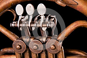 Vintage bronze pipes, valve, key mechanical elements french horn, black background. Good pattern, prompt music instrument.