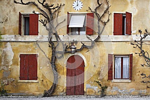 Vintage building facade with yellow wall and red shutters