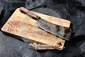 Vintage butcher meat cleaver on concrete board. Black background. Top view. Copy space