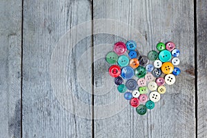 Vintage buttons in the shape of a heart on a wooden background