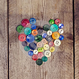 Vintage buttons in the shape of a heart on a wooden background