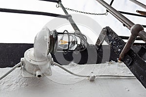 Vintage caged metal light fixture on the exterior of an old ship vessel, heavy paint