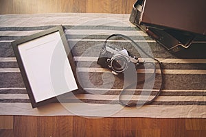 Vintage camera and blank photo frame on wooden table.