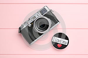Vintage camera and body cap with phrase I Love You on pink wooden background, flat lay