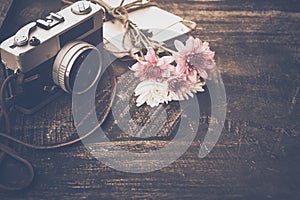 Vintage camera with bouquet of flowers on old wood background