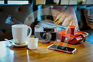 Vintage camera with coffee cup, glasses and smartphone on the ta