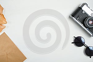 Vintage camera with dried leaves with craft paper envelope on a wooden white background