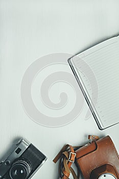 Vintage camera with leather case and diary on a wooden white background