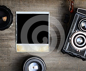 Vintage camera with lenses and blank old photograph on wooden background