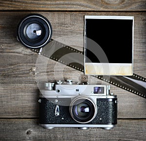 Vintage camera with lenses and blank old photograph on wooden background