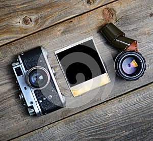 Vintage camera with lenses and blank old photograph on wooden background