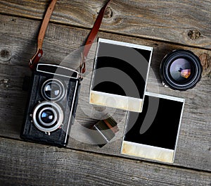 Vintage camera with lenses and blank old photograph on wooden background